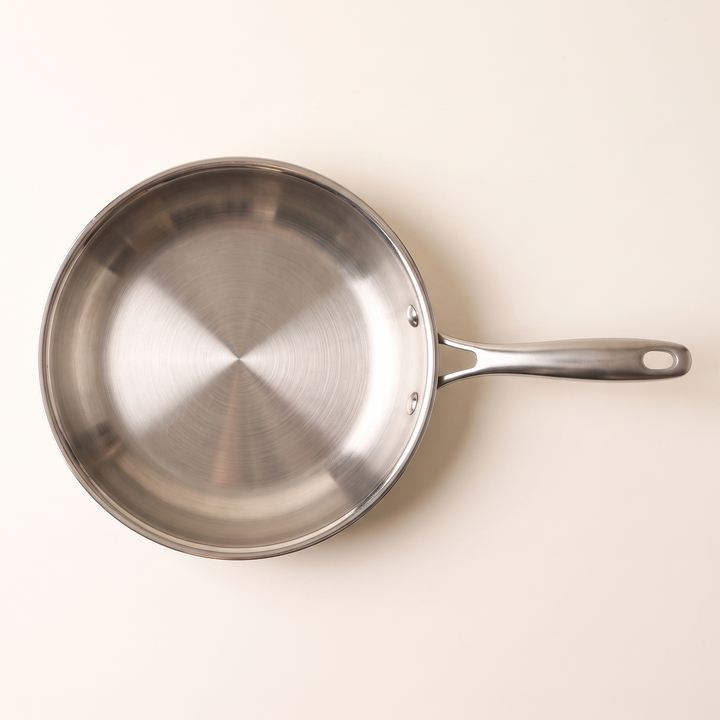 Poêle inox sans revêtement vue de dessus, le brossage concentrique du fond bien visible
